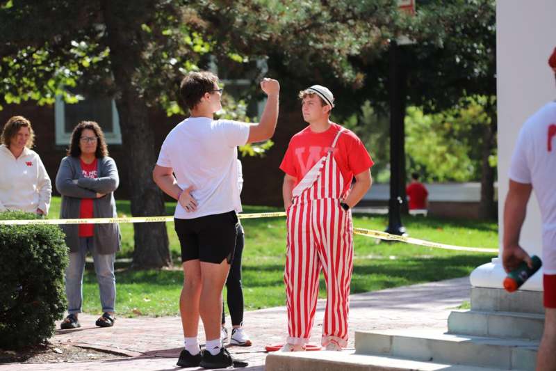 a man in striped pants standing next to a man in a red and white striped outfit