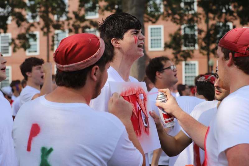 a group of people holding a spray can and a man with paint on his face