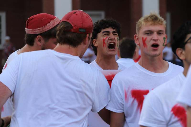 a group of men wearing white shirts with red paint on their faces