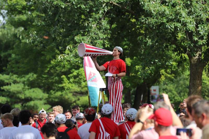 a man in red and white striped pants with a megaphone in front of a crowd
