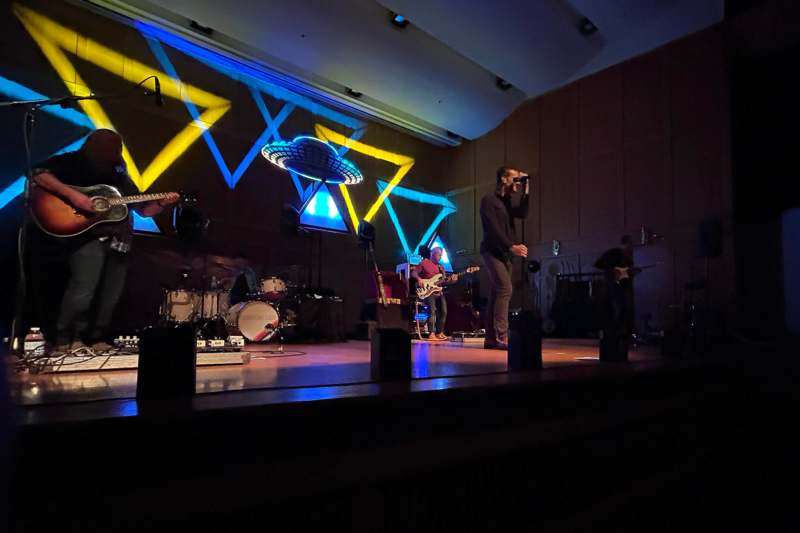 a man singing on a stage with a band on it
