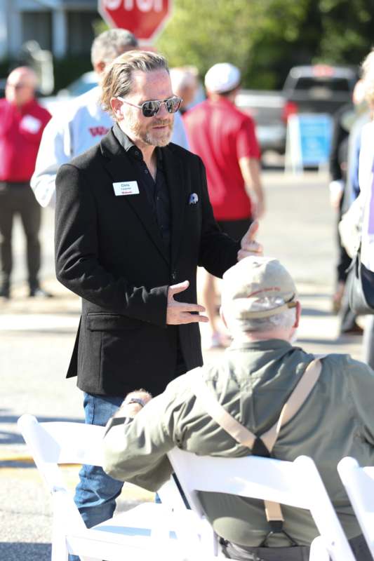 a man in a black jacket talking to a man in a hat