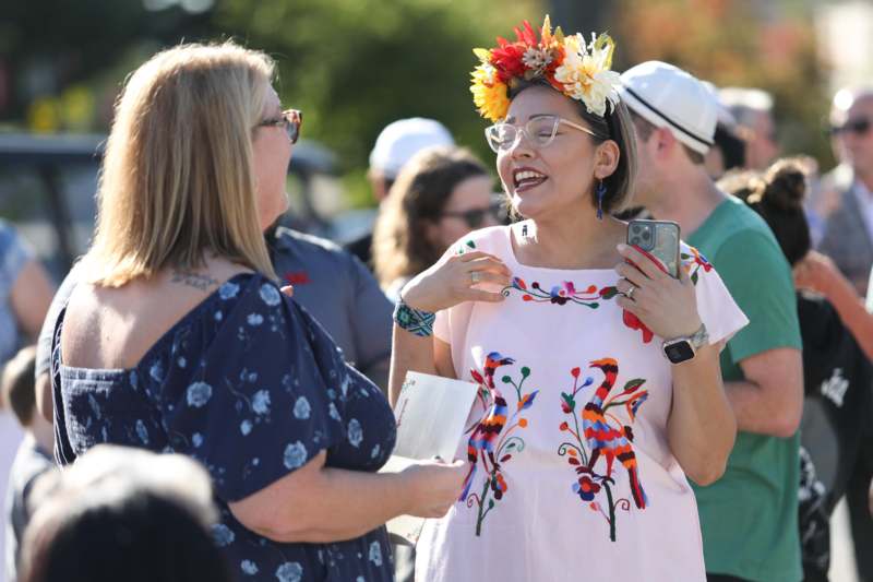 a woman with flowers on her head and a woman with a phone