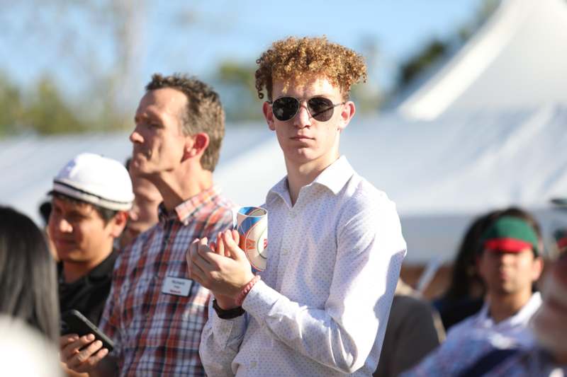 a man wearing sunglasses and holding a cup