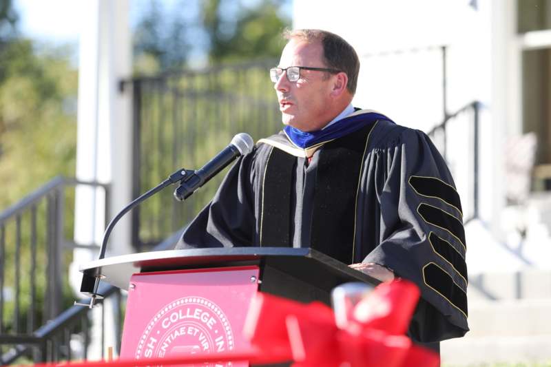 a man in a graduation gown speaking into a microphone