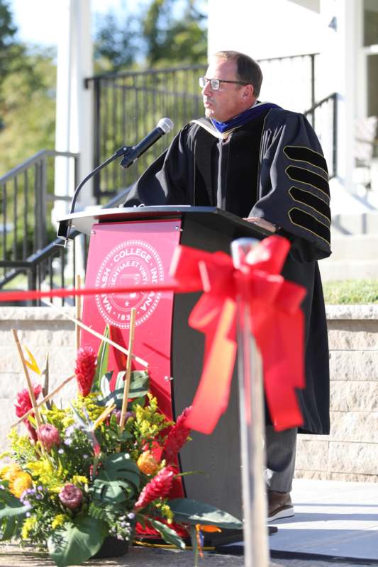 a man in a graduation gown standing at a podium