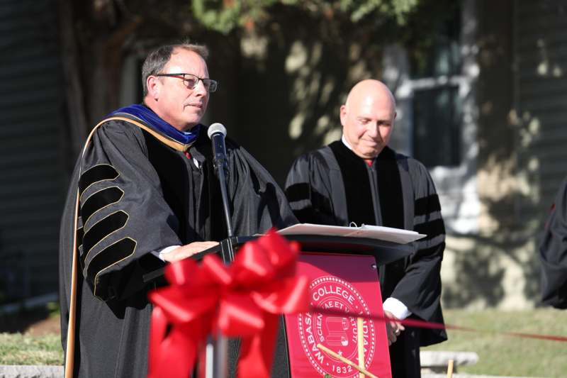 a man in black robe standing at a podium with a microphone
