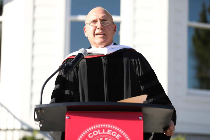 a man in a graduation gown standing at a podium