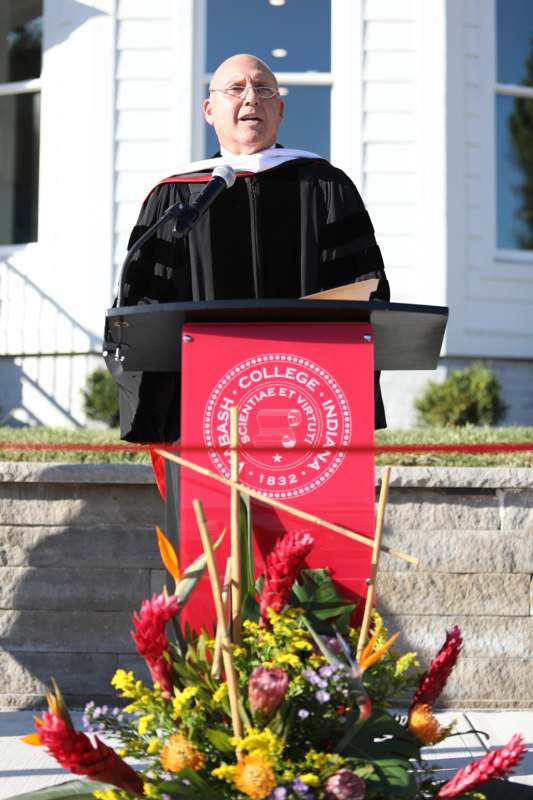 a man in a graduation gown standing at a podium