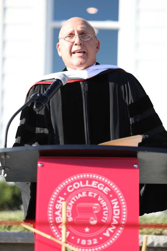 a man in a graduation gown standing at a podium