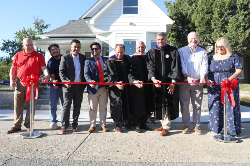 a group of people cutting a red ribbon