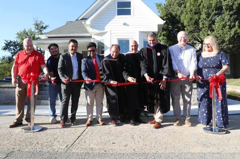 a group of people cutting a red ribbon