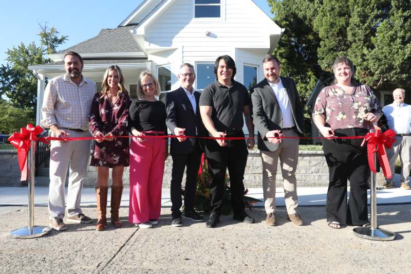 a group of people cutting a red ribbon