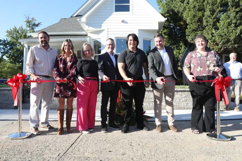 a group of people cutting a red ribbon