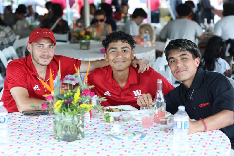 a group of men sitting at a table with food and drinks