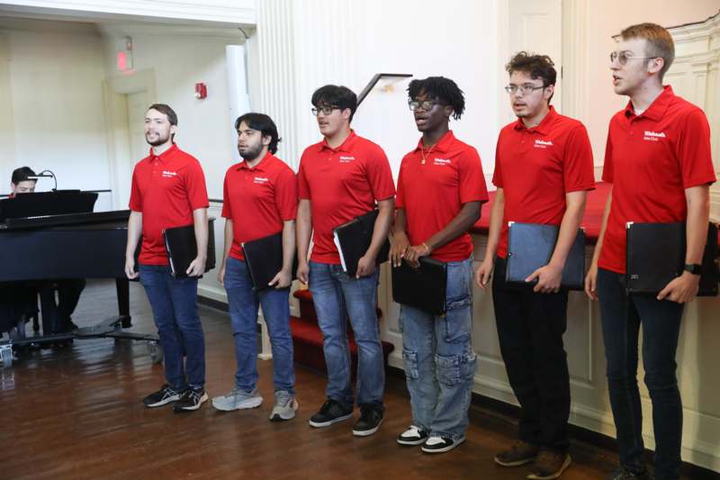 a group of men in red shirts holding laptops