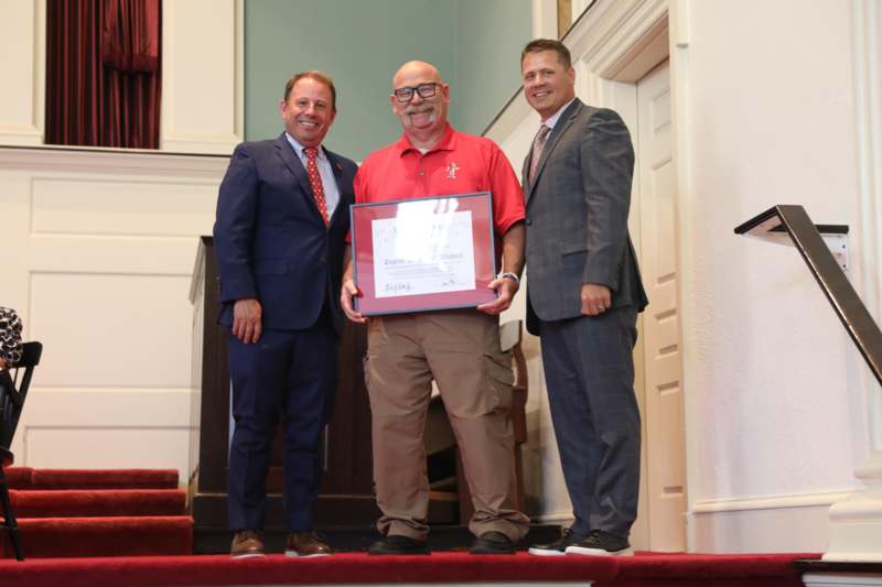 a group of men standing on stairs holding a certificate