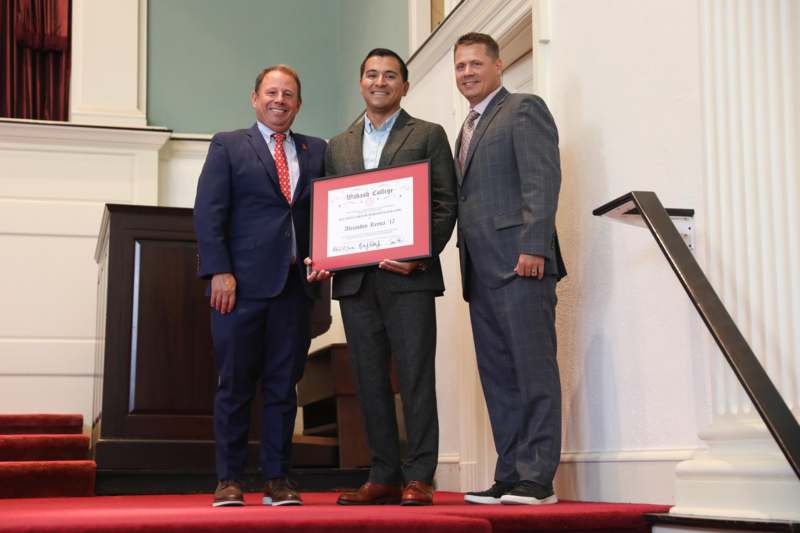 a group of men standing on a red carpet holding a certificate