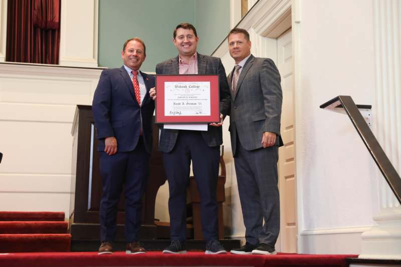 a group of men standing on a red carpet holding a certificate