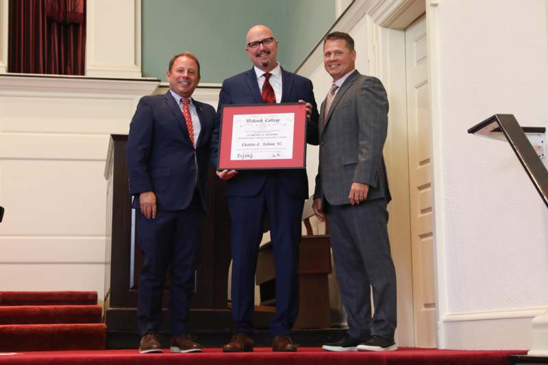 a group of men standing on stairs and holding a certificate