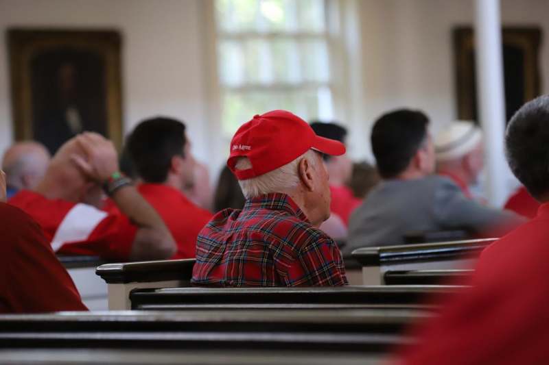 a man in a red hat sitting in a church