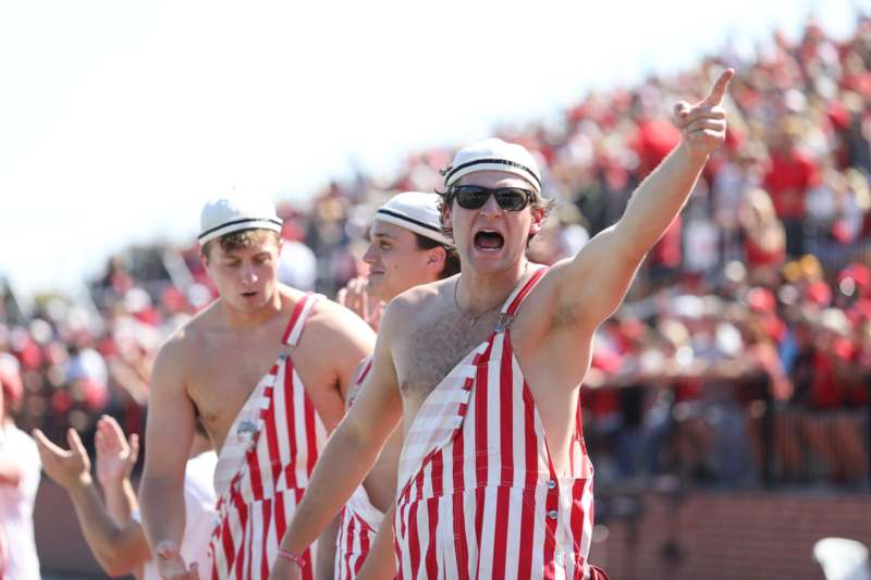 a group of men wearing red and white striped overalls and white hats