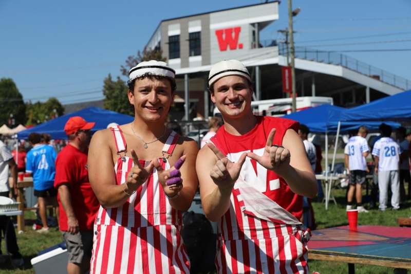 two men wearing striped overalls and holding up their hands