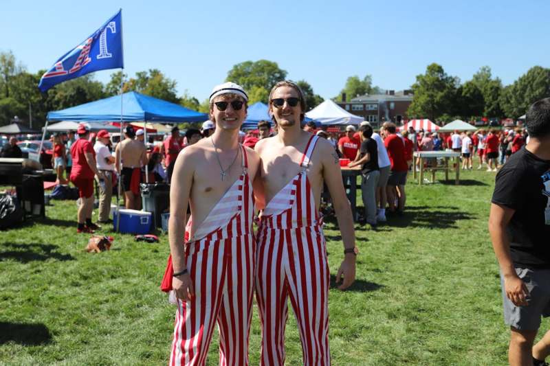 two men wearing striped overalls standing in a field