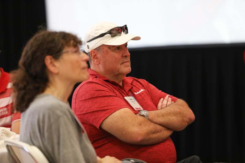 a man in a red shirt and white hat with his arms crossed