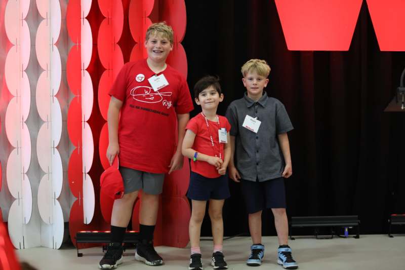 a group of boys standing in front of a red and black backdrop