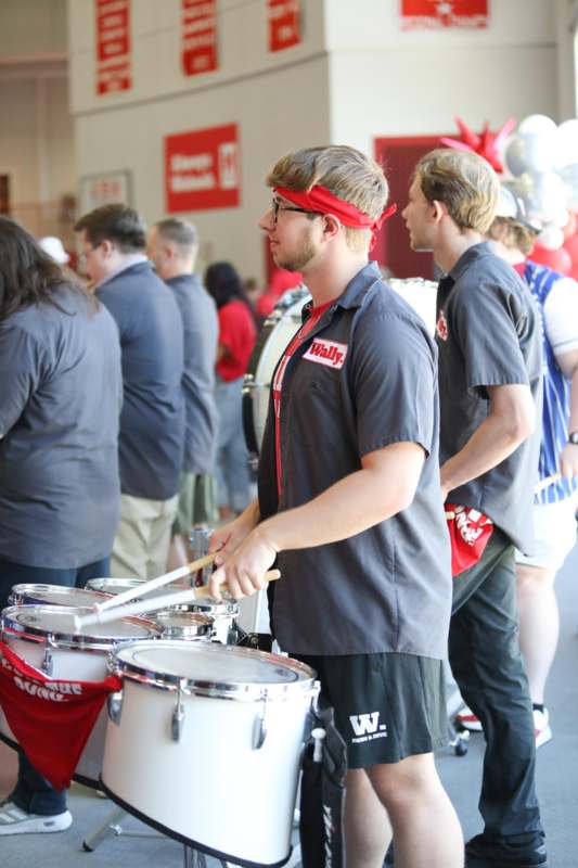 a man playing drums with other people in the background