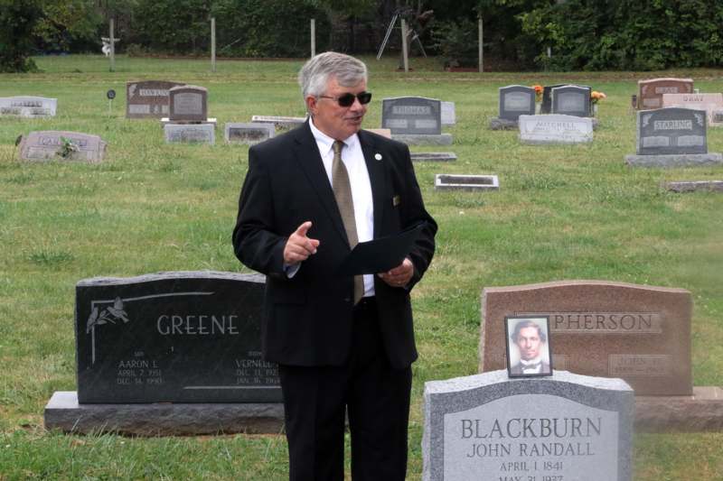 a man in a suit standing in a cemetery