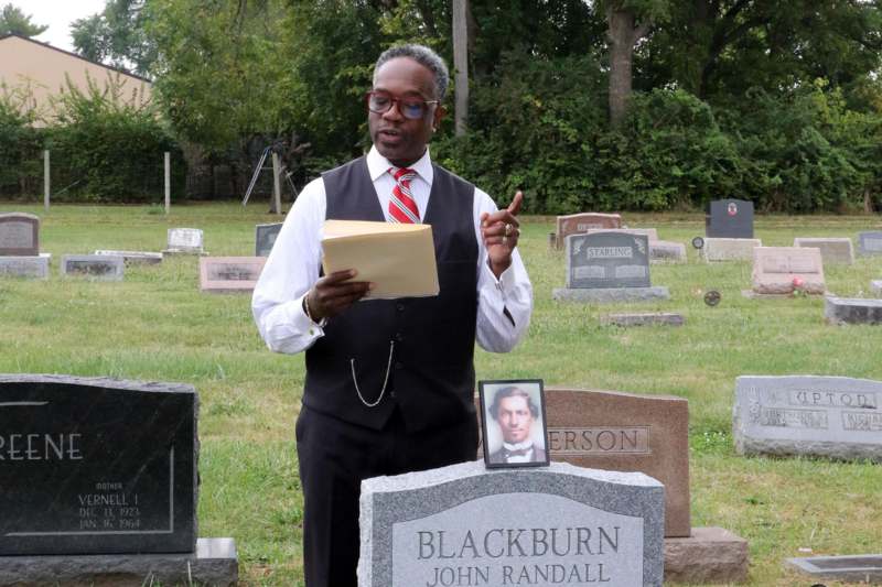 a man standing in a cemetery holding a file