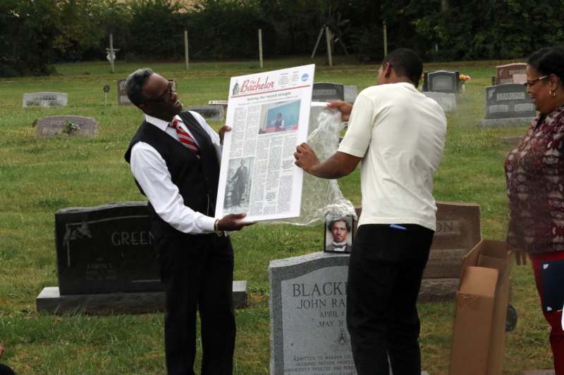 a man holding a newspaper in a cemetery