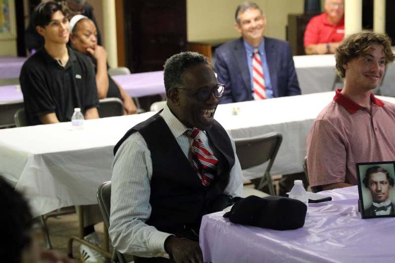 a man sitting at a table with people in the background