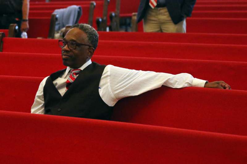 a man in a vest and tie sitting on a red bench