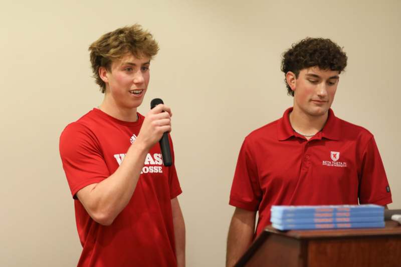 a man in red shirts holding a microphone