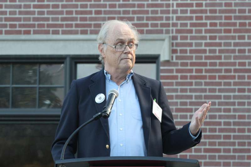a man standing at a podium with his hand up