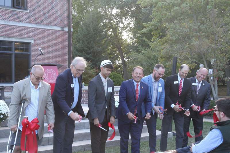 a group of men in suits cutting a man's body