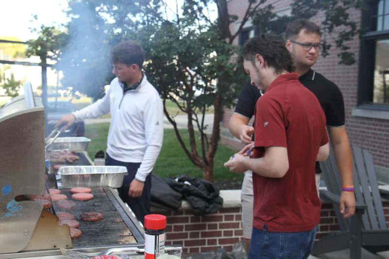 a group of men cooking burgers on a grill