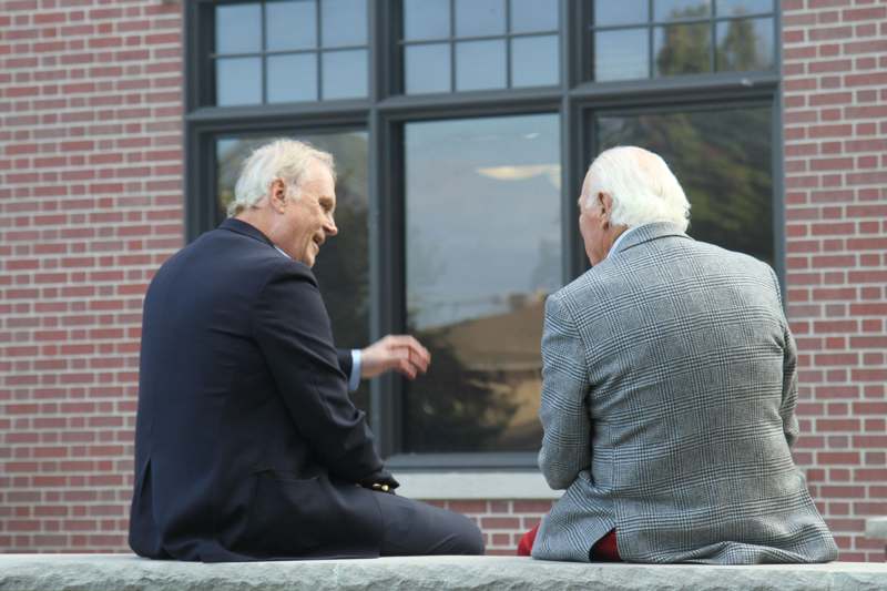 two men sitting on a ledge