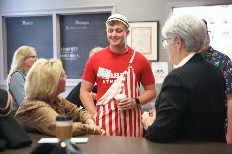 a man in an apron holding a cup of coffee