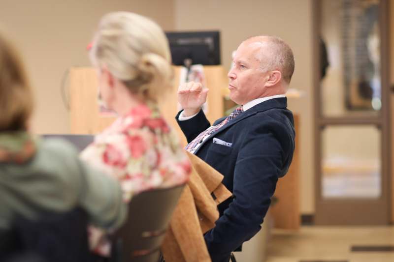 a man in a suit and tie sitting in chairs