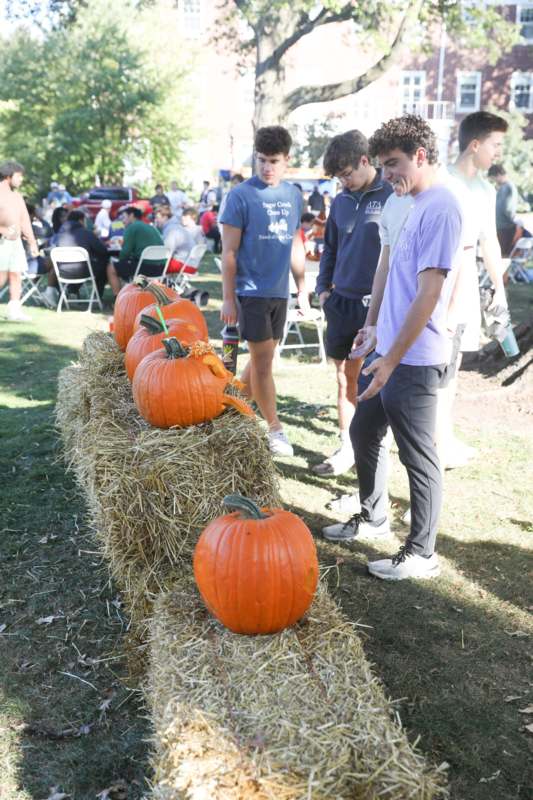 a group of people standing next to a pumpkin