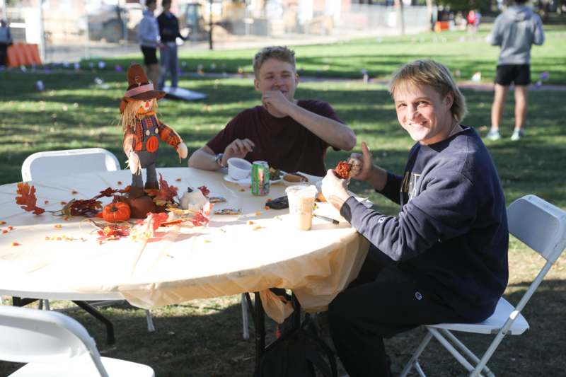 a group of men sitting at a table with a scarecrow