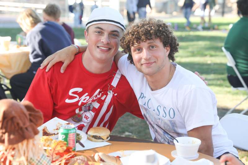 two men sitting at a table with food and drinks