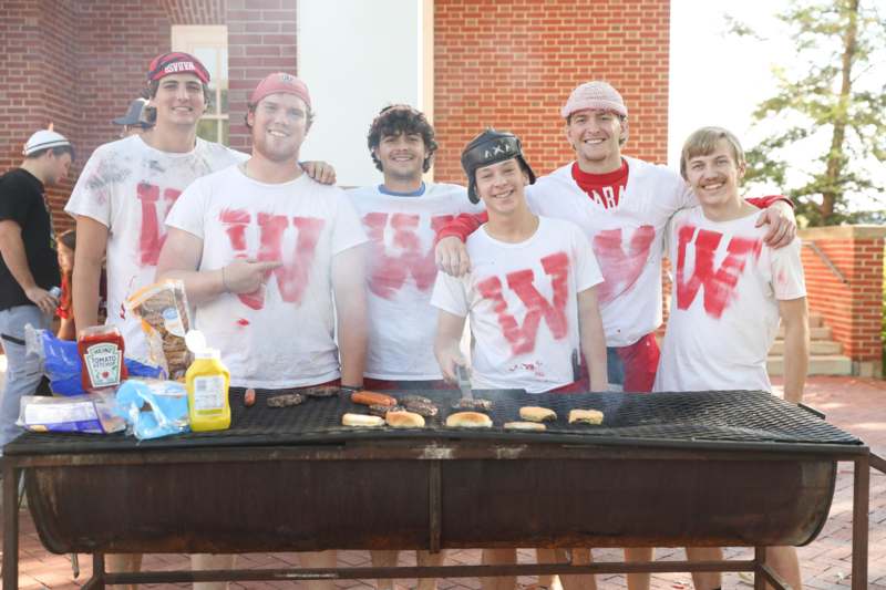 a group of men wearing white t-shirts with red letters on them