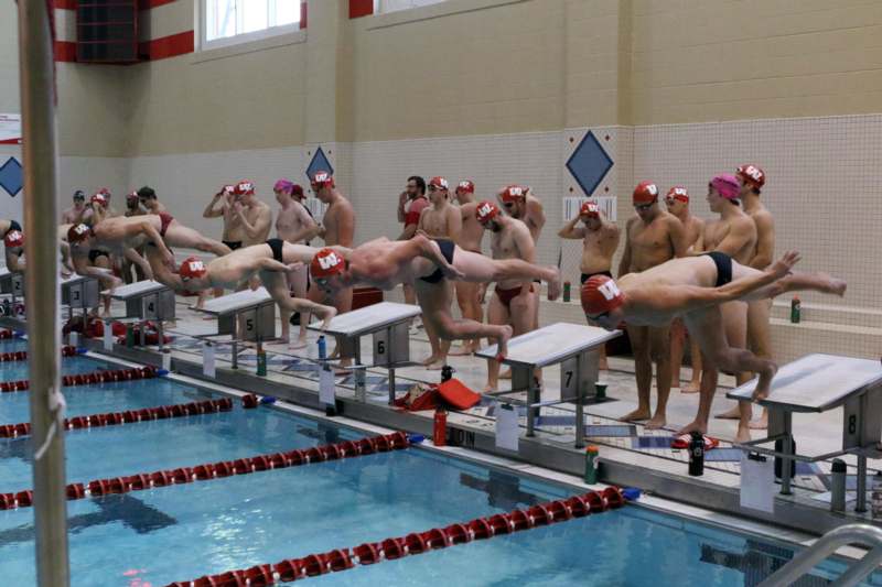 a group of people in swim caps diving into a pool