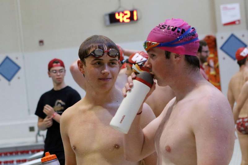 a group of men in a swimming pool drinking from a white bottle
