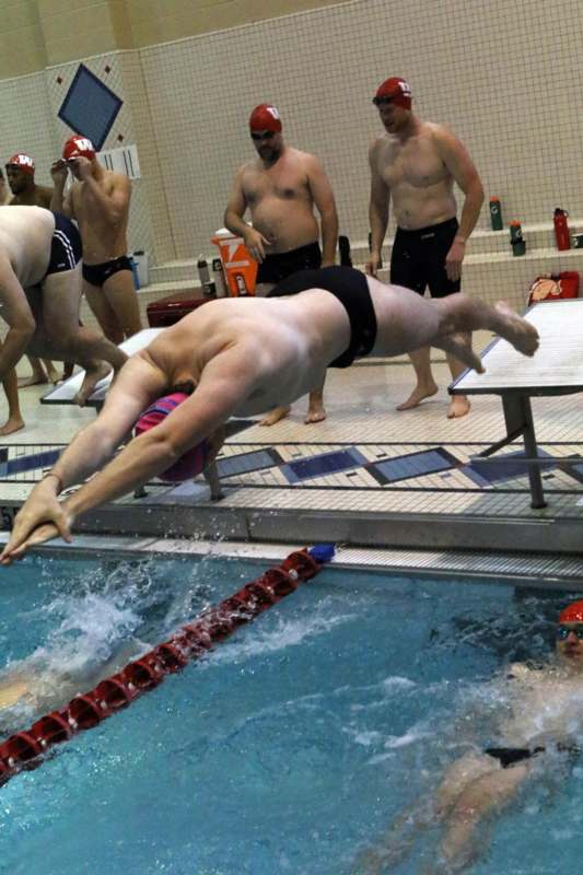 a group of men in swimsuits diving into a pool